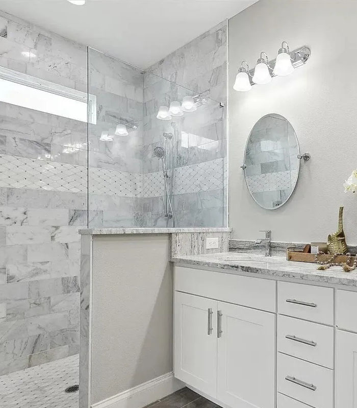 Spacious bathroom with walk-in shower, round mirrors and white capinets.