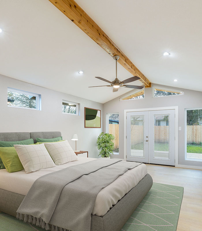 Bright and airy florida bedroom with ceiling fan, wood accents and large double patio doors