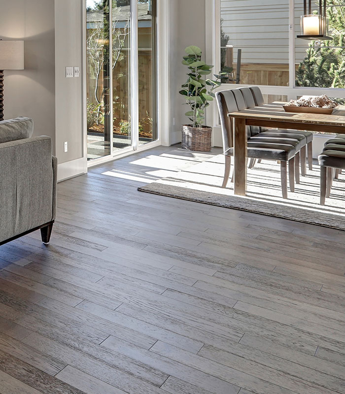 Dark gray, weathered engineered wood floors in a Florida Style open floor plan
