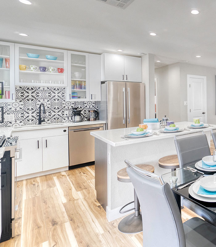 open kitchen with high ceilings in white and stainless with wood-look waterproof vinyl floor planks